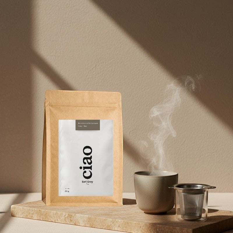 Say Ciao Coffee Earl Grey tea bag with a cup of steaming tea and infuser on a marble slab.