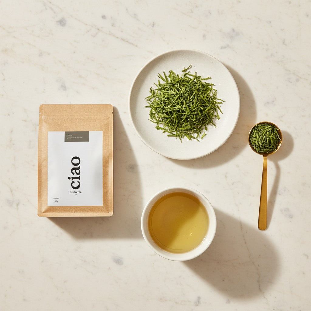 Say Ciao Coffee green tea leaves in a pouch, on a plate, in a golden spoon, and brewed in a white cup.
