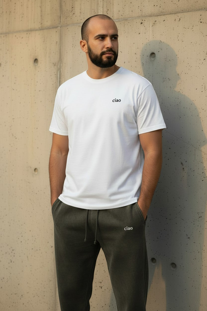 Say Ciao Coffee dark olive washed cotton blend joggers with adjustable drawstring and logo detail. Model has hands in pockets.