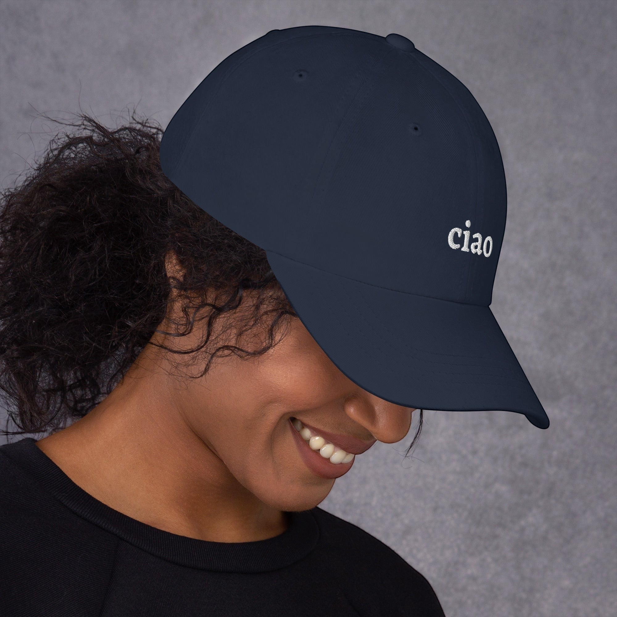Say Ciao Coffee navy blue cotton twill baseball cap with embroidered "ciao" detail and curved visor, worn by a smiling woman.